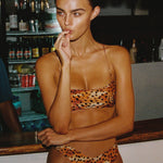 Model wearing a leopard print bikini in a bar setting