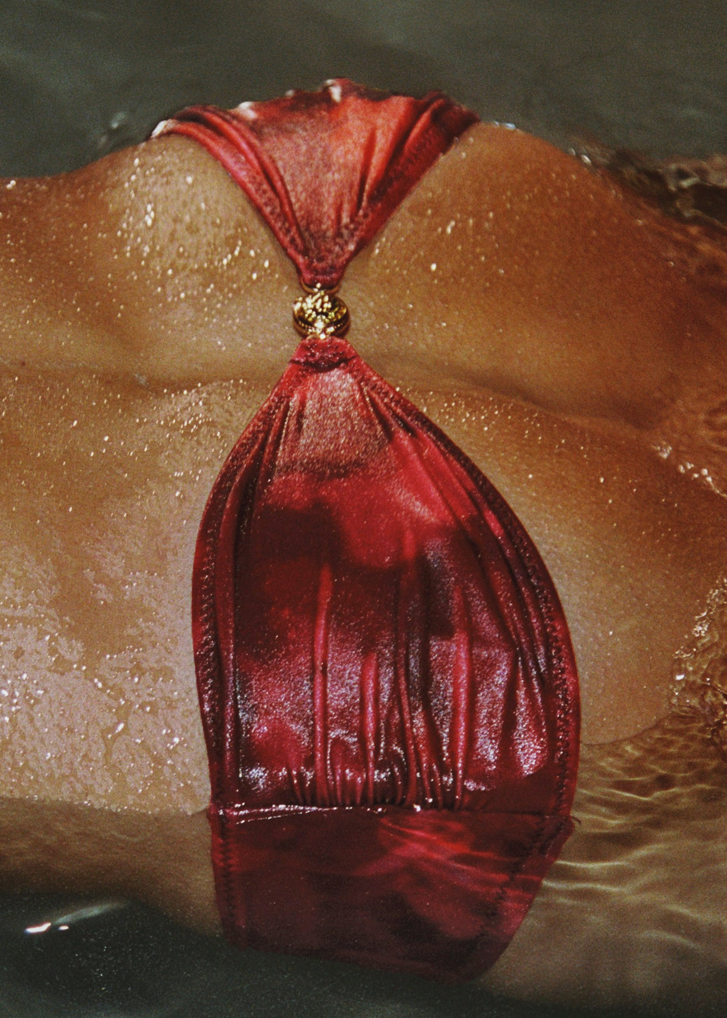Red leather bag with a gold clasp on a textured surface